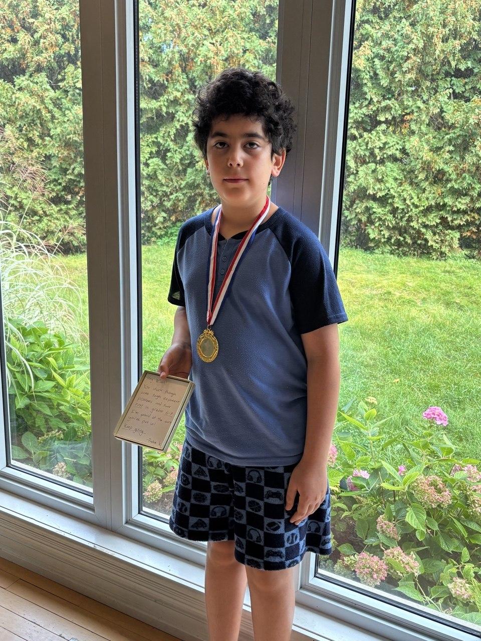 September HOPE Contest winner in a blue shirt, wearing a gold medal and holding a handwritten note