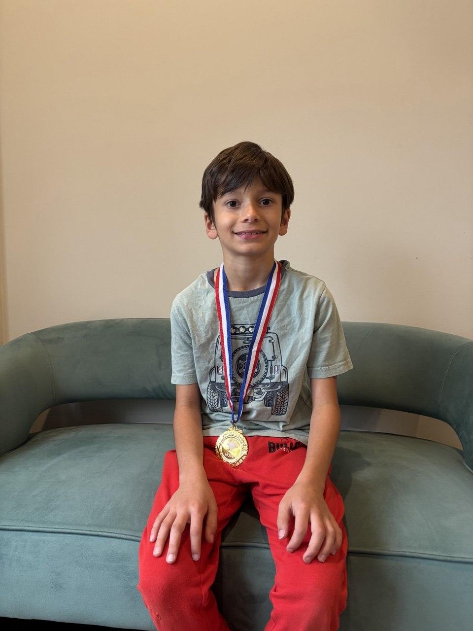 September HOPE Contest winner sitting on a green sofa with a gold medal